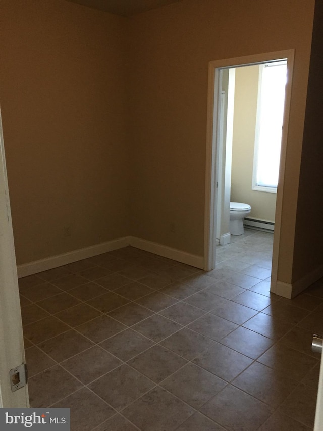 unfurnished room featuring baseboard heating and tile patterned floors