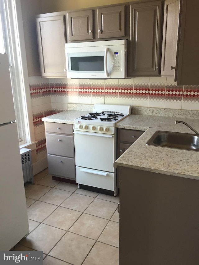 kitchen featuring sink, white appliances, radiator, light tile patterned floors, and tasteful backsplash