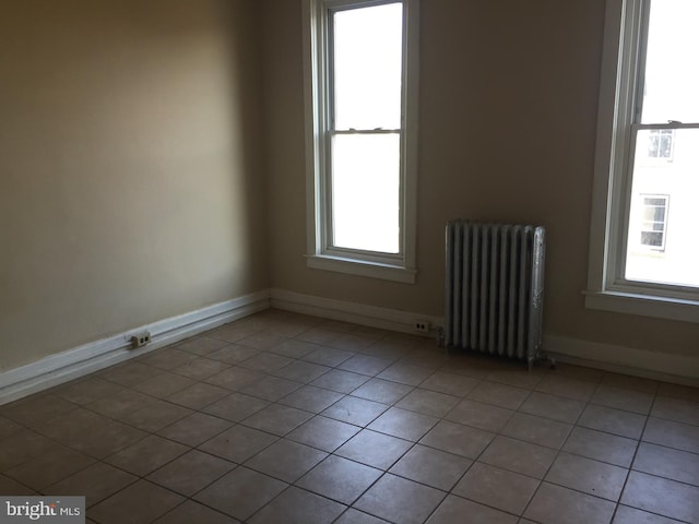 unfurnished room with radiator and light tile patterned floors