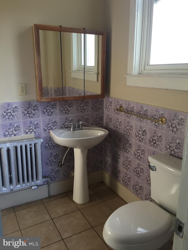 bathroom with tile patterned flooring, a healthy amount of sunlight, radiator heating unit, and toilet