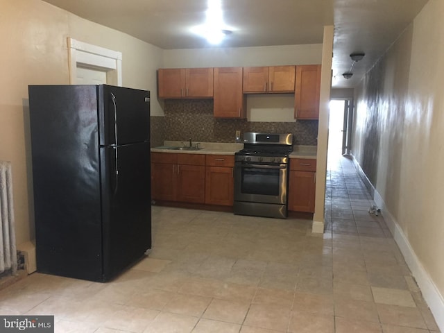 kitchen with radiator, black refrigerator, stainless steel gas stove, sink, and decorative backsplash