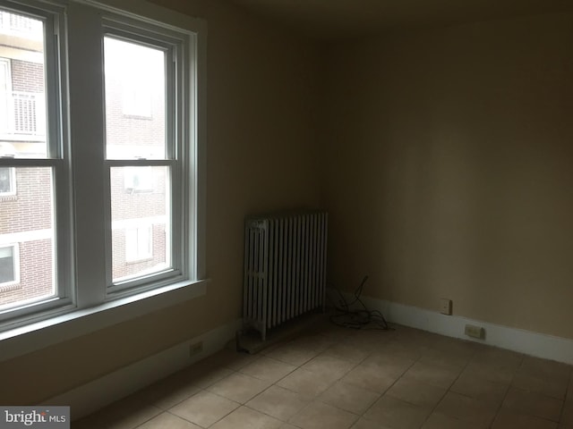 empty room with radiator and light tile patterned floors