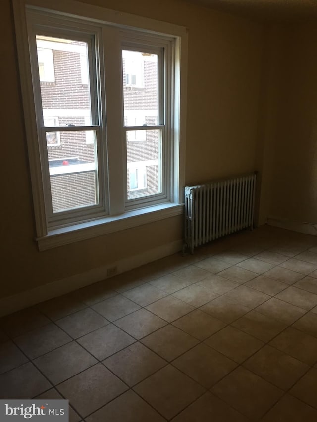 spare room with tile patterned floors and radiator