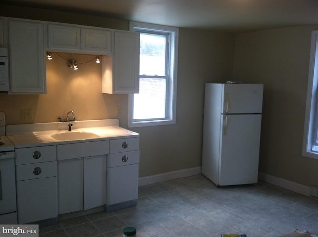 kitchen featuring sink, white cabinets, and white appliances