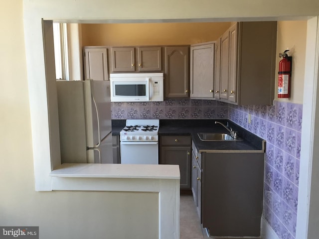 kitchen featuring sink, tasteful backsplash, light tile patterned floors, kitchen peninsula, and white appliances