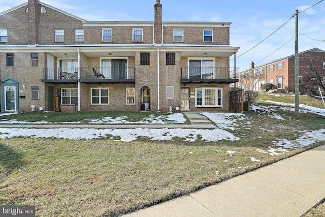 townhome / multi-family property with central AC, a balcony, and a front lawn