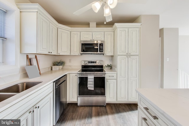 kitchen with sink, dark wood-type flooring, ceiling fan, stainless steel appliances, and light stone countertops