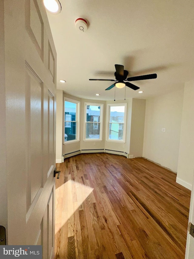 spare room with light hardwood / wood-style floors, ceiling fan, and baseboard heating