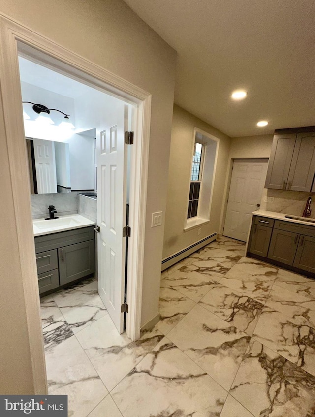 bathroom featuring a baseboard heating unit, sink, and backsplash