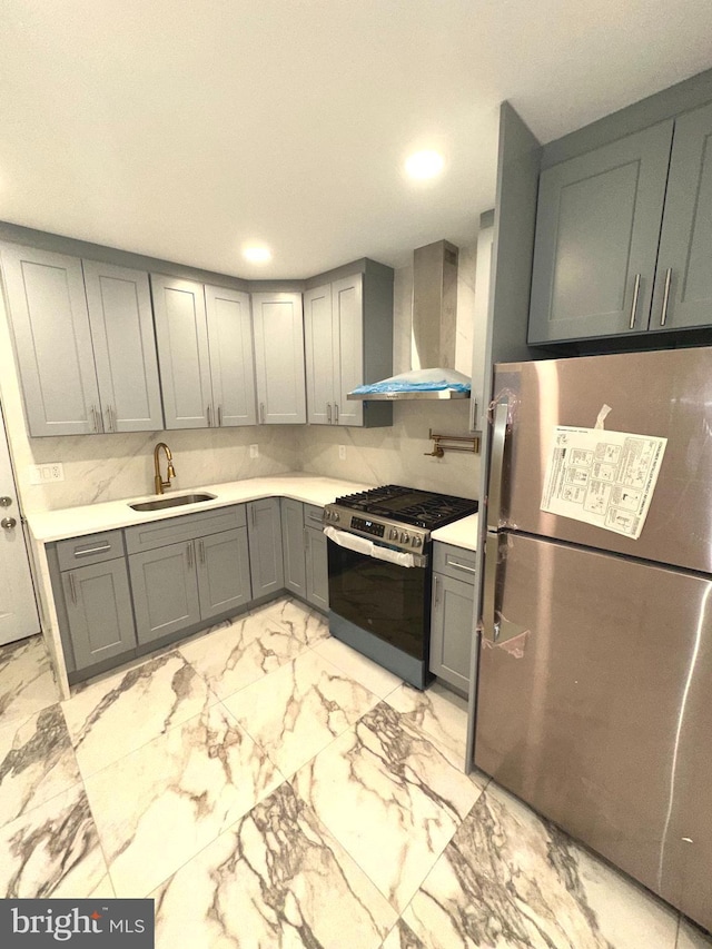 kitchen with stainless steel appliances, sink, wall chimney range hood, and gray cabinetry