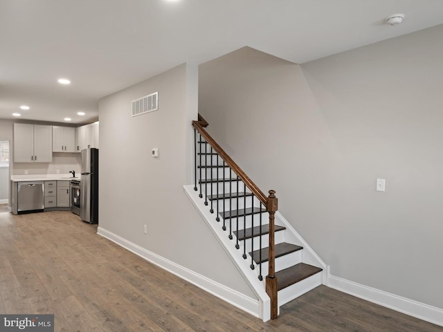 stairs with wood-type flooring and sink