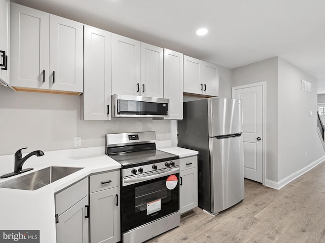 kitchen featuring white cabinetry, appliances with stainless steel finishes, sink, and light hardwood / wood-style flooring