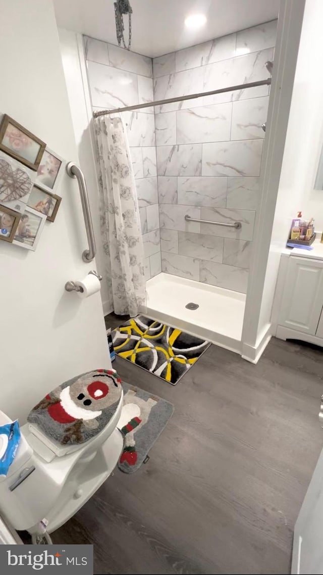 bathroom with hardwood / wood-style flooring, vanity, toilet, and curtained shower