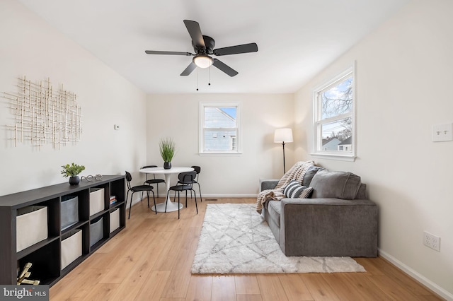 living room featuring a healthy amount of sunlight, light hardwood / wood-style floors, and ceiling fan