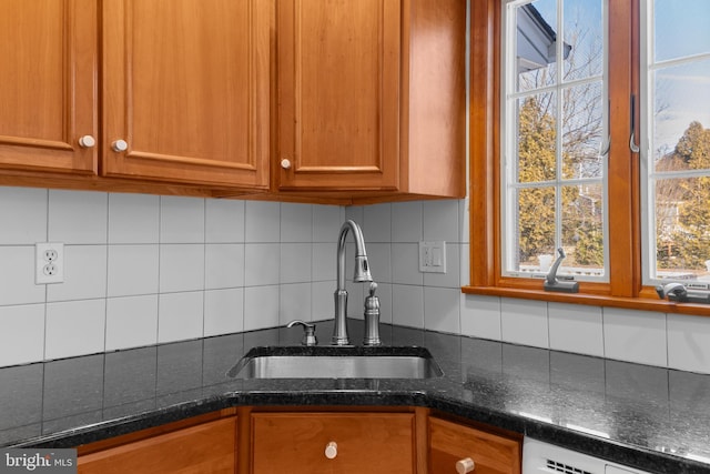 kitchen with sink, backsplash, dark stone counters, and dishwasher