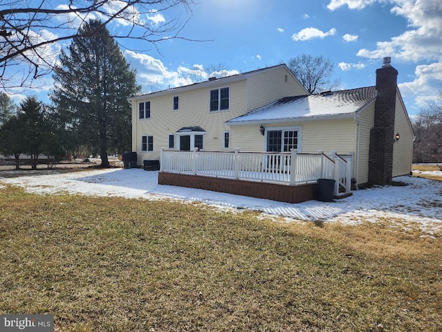 snow covered rear of property featuring a wooden deck and a yard