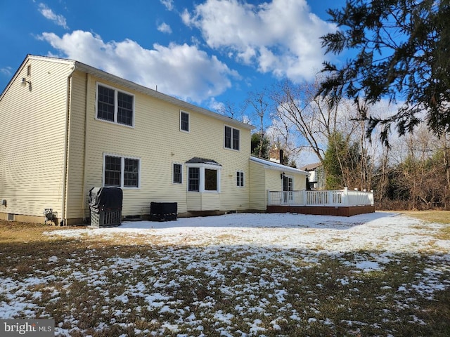 snow covered back of property with a wooden deck