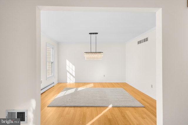 unfurnished dining area with ornamental molding, a baseboard heating unit, and hardwood / wood-style floors