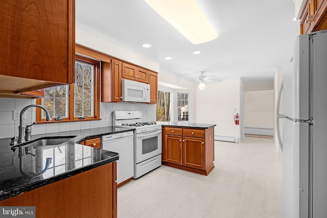 kitchen featuring sink, dark stone countertops, a baseboard heating unit, kitchen peninsula, and white appliances