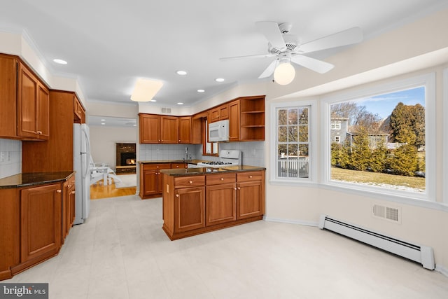 kitchen with sink, white appliances, baseboard heating, dark stone countertops, and kitchen peninsula