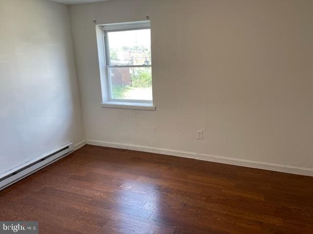 unfurnished room with a baseboard radiator and dark hardwood / wood-style flooring