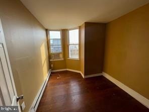 spare room with a baseboard heating unit and dark wood-type flooring