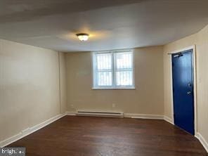 spare room featuring dark wood-type flooring and a baseboard radiator