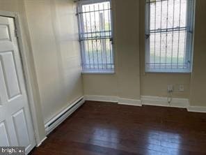 spare room with dark wood-type flooring and a baseboard radiator