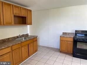 kitchen featuring dark stone countertops, sink, electric range, and light tile patterned floors