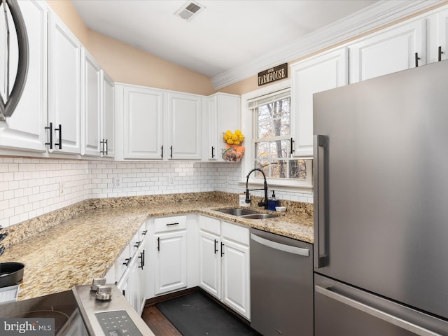 kitchen with sink, stainless steel appliances, light stone countertops, white cabinets, and decorative backsplash