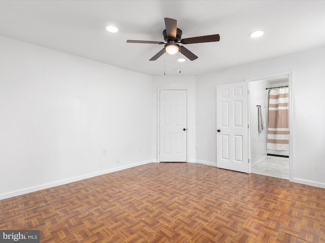 unfurnished bedroom featuring ceiling fan, ensuite bath, and dark parquet flooring