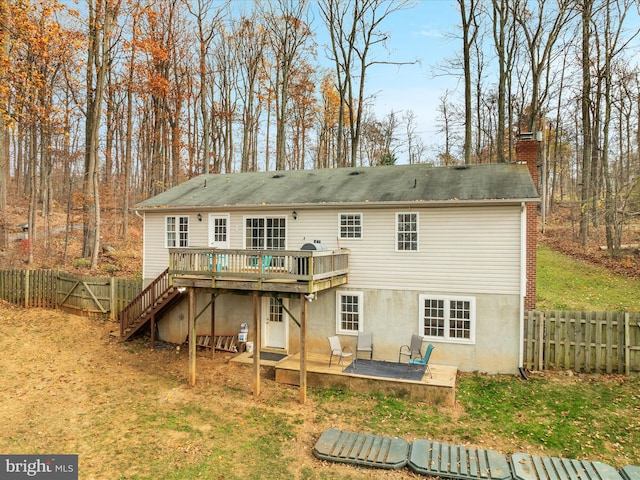 back of property featuring a wooden deck, a patio, and a lawn