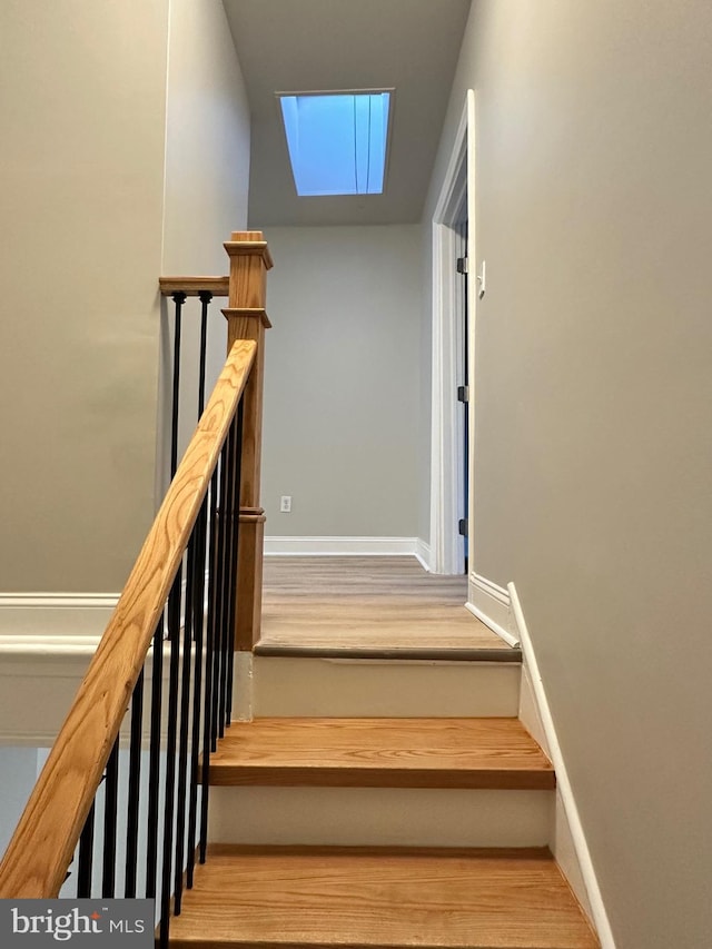 staircase with hardwood / wood-style flooring and a skylight