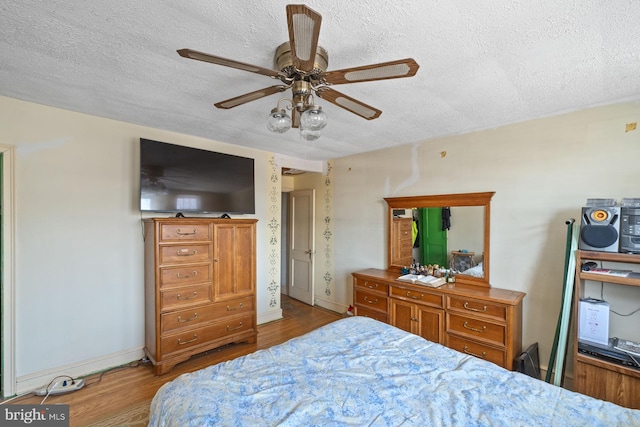 bedroom with ceiling fan, light hardwood / wood-style floors, and a textured ceiling