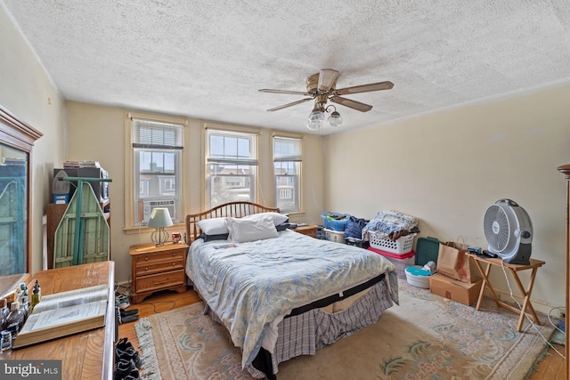 bedroom featuring cooling unit, a textured ceiling, ceiling fan, and light wood-type flooring