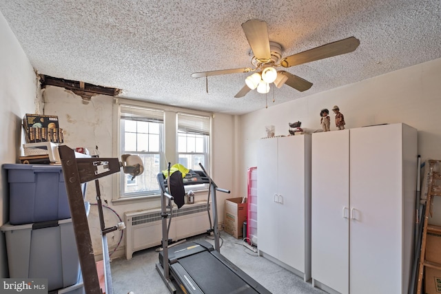 workout area featuring light carpet, radiator heating unit, and a textured ceiling