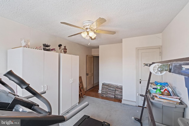 exercise area featuring ceiling fan and a textured ceiling