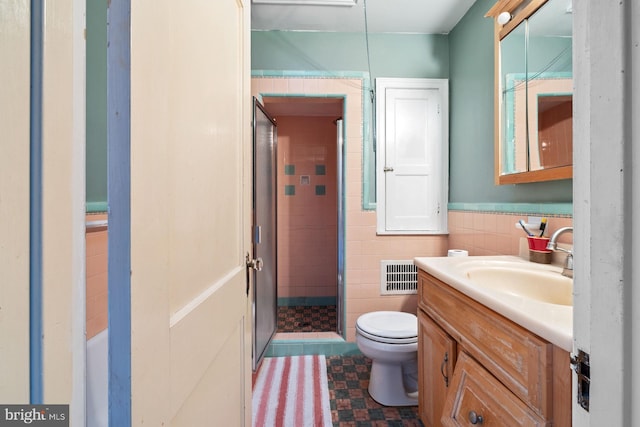 bathroom with vanity, toilet, tile walls, and a tile shower