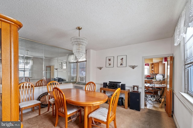 carpeted dining area with a notable chandelier, plenty of natural light, and a textured ceiling