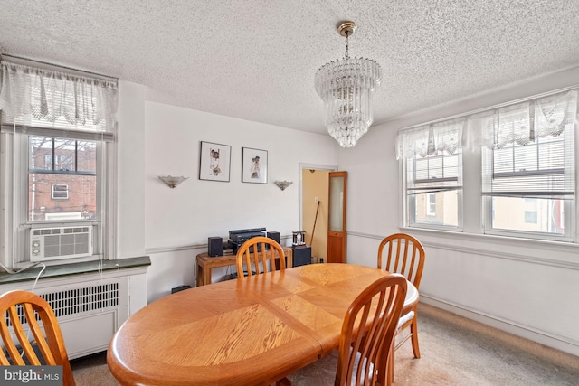 dining room featuring a chandelier, a textured ceiling, carpet flooring, radiator, and cooling unit