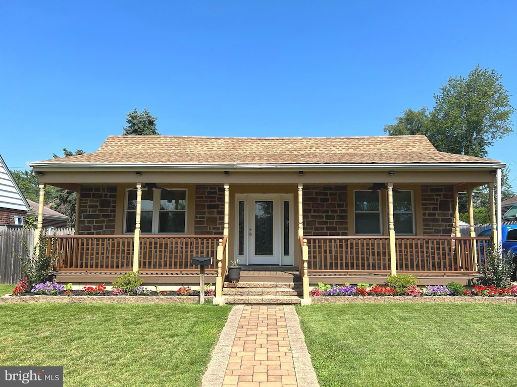 view of front facade featuring ceiling fan, covered porch, and a front lawn