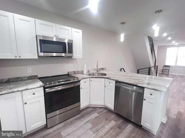 kitchen featuring stainless steel appliances, pendant lighting, and white cabinets