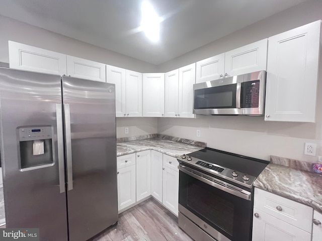 kitchen featuring light stone countertops, light hardwood / wood-style flooring, stainless steel appliances, and white cabinets