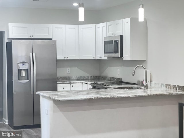 kitchen with hanging light fixtures, appliances with stainless steel finishes, white cabinets, and light stone counters