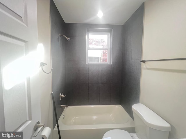 bathroom featuring tiled shower / bath combo and toilet