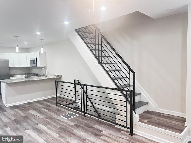 stairway featuring sink and wood-type flooring