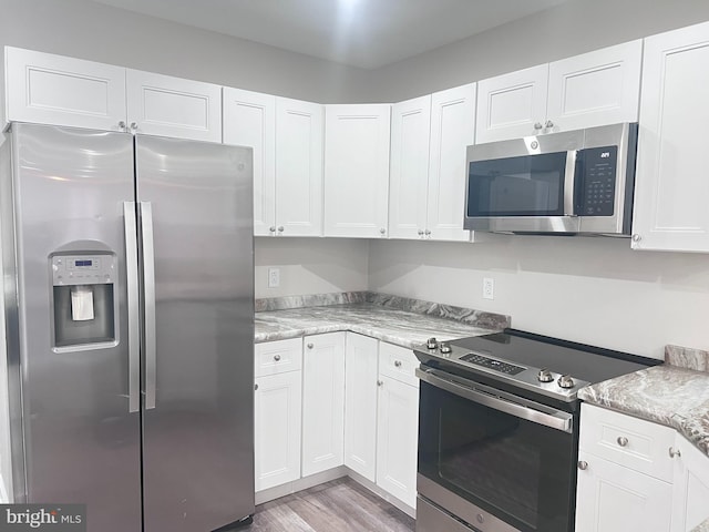 kitchen featuring white cabinetry, stainless steel appliances, and light stone countertops