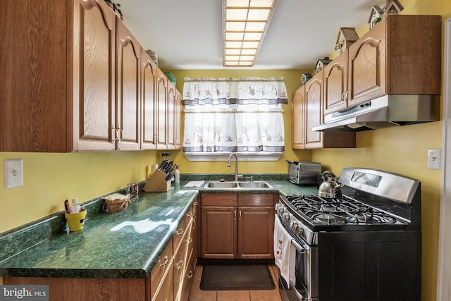 kitchen featuring sink, stainless steel gas range oven, and dark tile patterned flooring