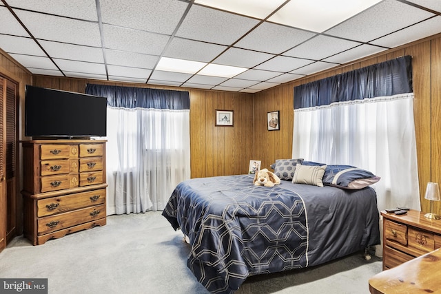 bedroom featuring a paneled ceiling, light carpet, and wood walls