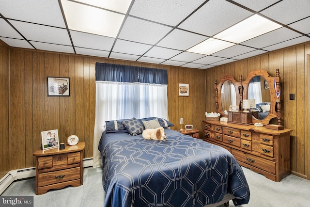 bedroom featuring wooden walls, a baseboard radiator, carpet flooring, and a drop ceiling